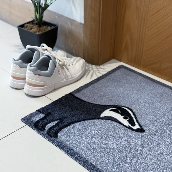 Badger Doormat closeup with trainers and plant
