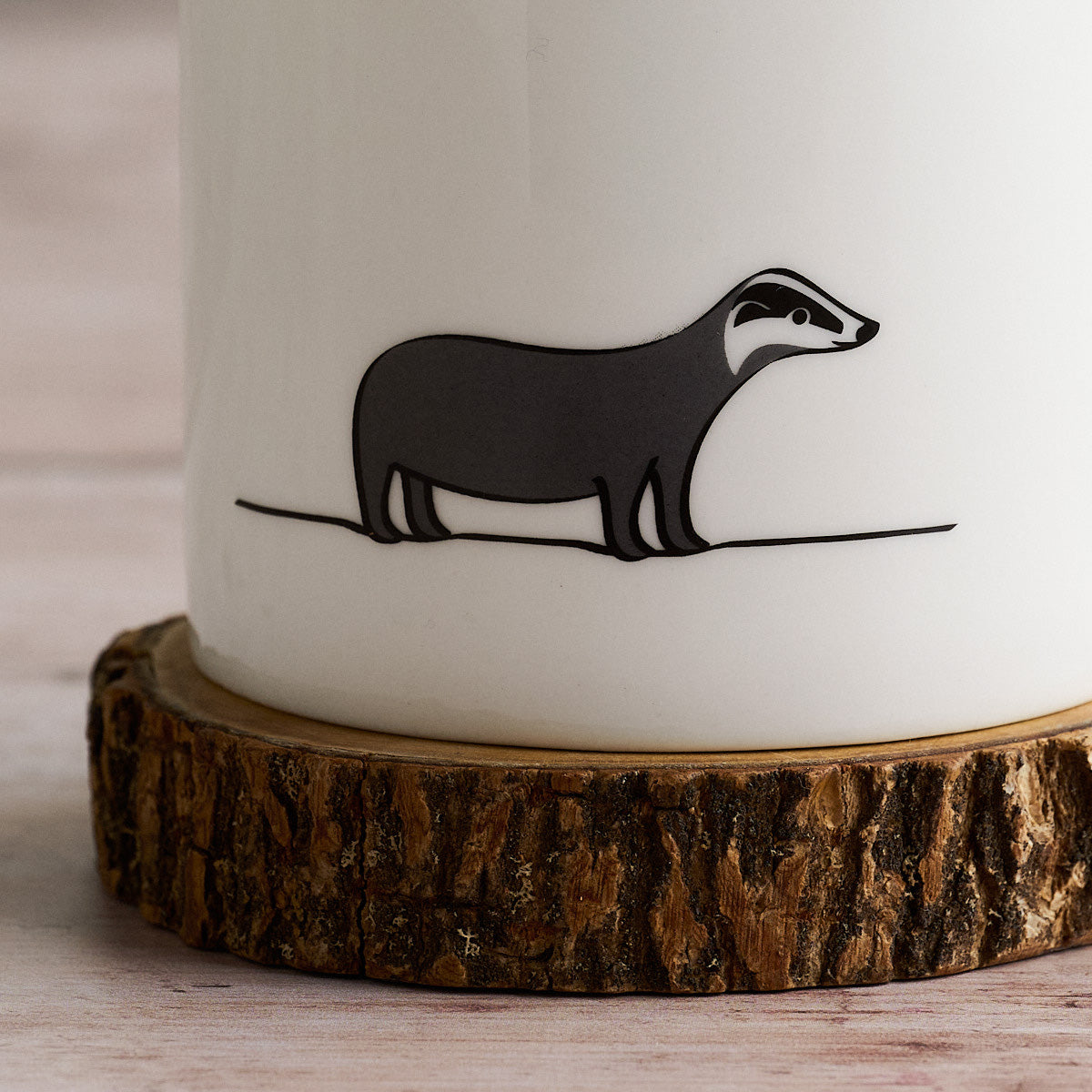 White mug with Badger on a wooden coaster