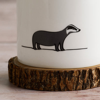 White mug with Badger on a wooden coaster