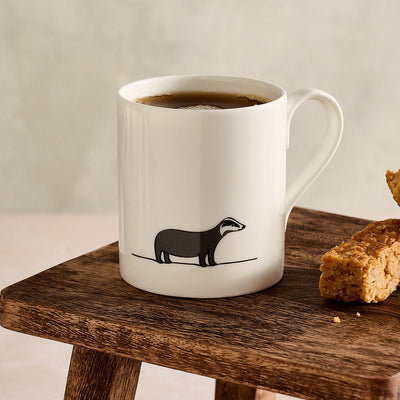 White mug with Badger design on a wooden surface with flapjack