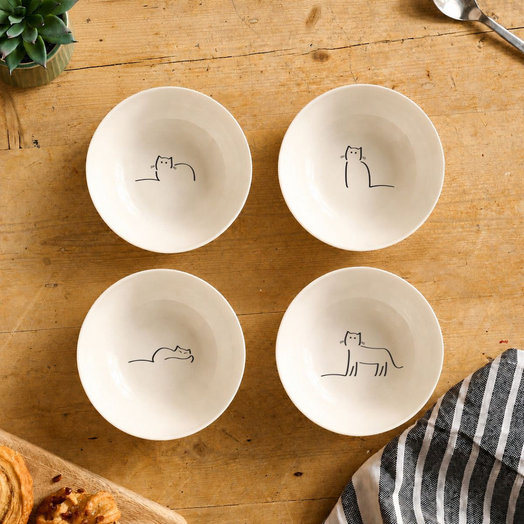 Four white bowls with Cat Companions on a wooden table