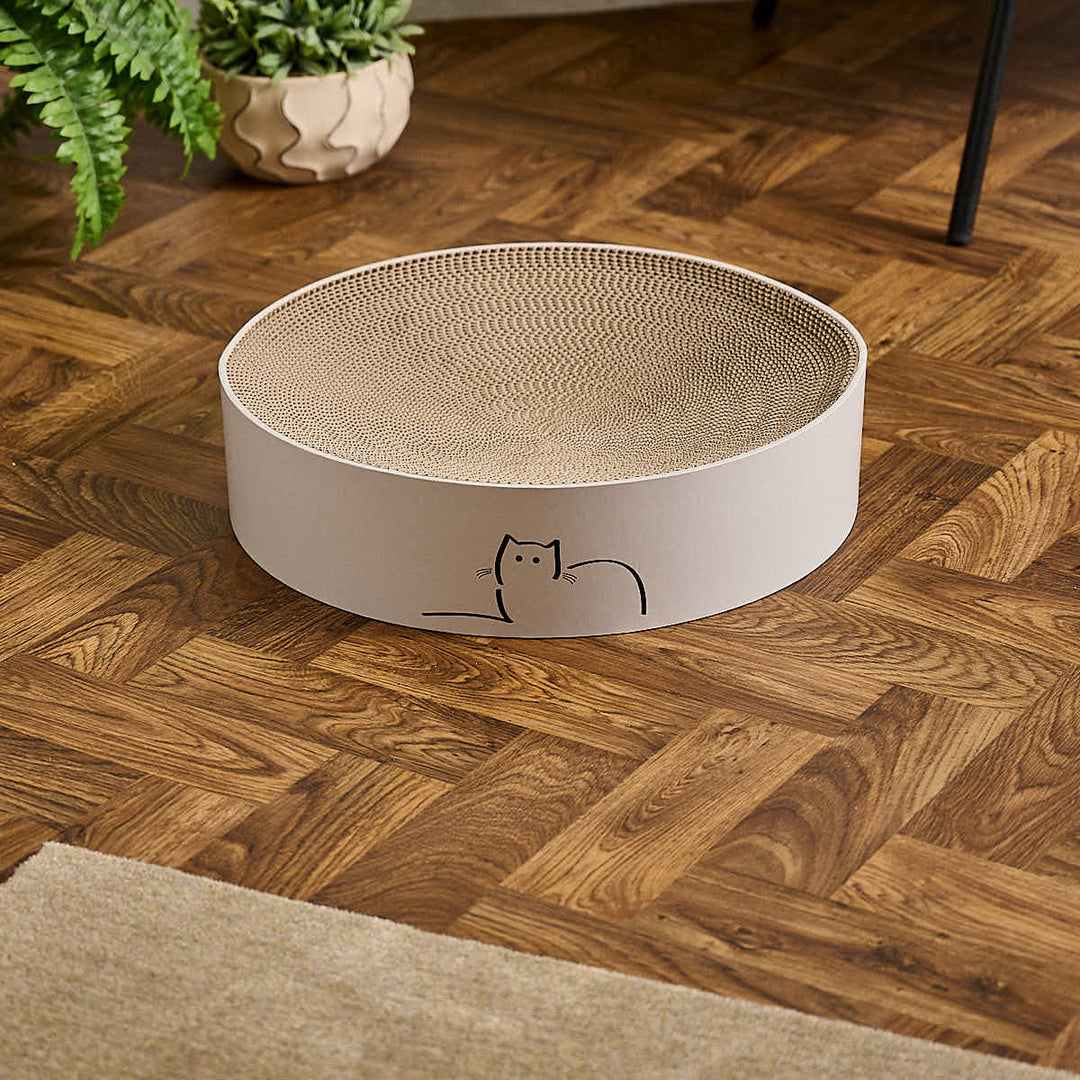 Special edition CatLoaf round cat scratcher featuring Loafing Cat - placed on a wooden parquet floor.