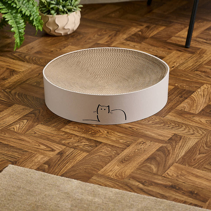 Special edition CatLoaf round cat scratcher featuring Loafing Cat - placed on a wooden parquet floor.