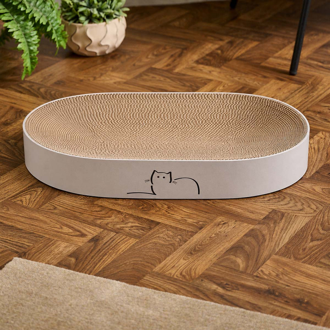 An oval-shaped CatLoaf cat scratcher bed with Loafing Cat on wooden floor