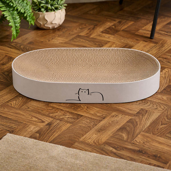 An oval-shaped CatLoaf cat scratcher bed with Loafing Cat on wooden floor