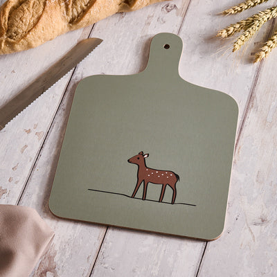 Soft Sage Green Chopping Board with a deer illustration on a wooden surface with bread and wheat.