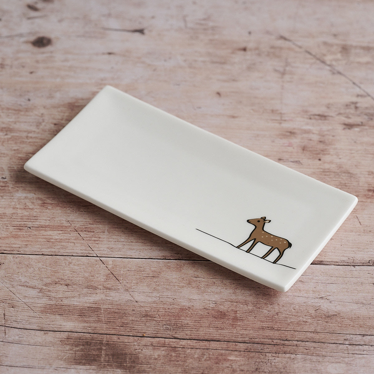 Rectangular white mini tray with a deer illustration on a wooden surface