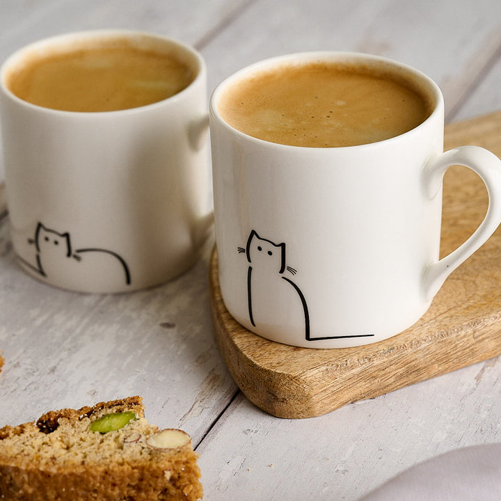 Cat Espresso Mugs, Set of Two with Loafing Cat and Waiting Cat close up with biscotti