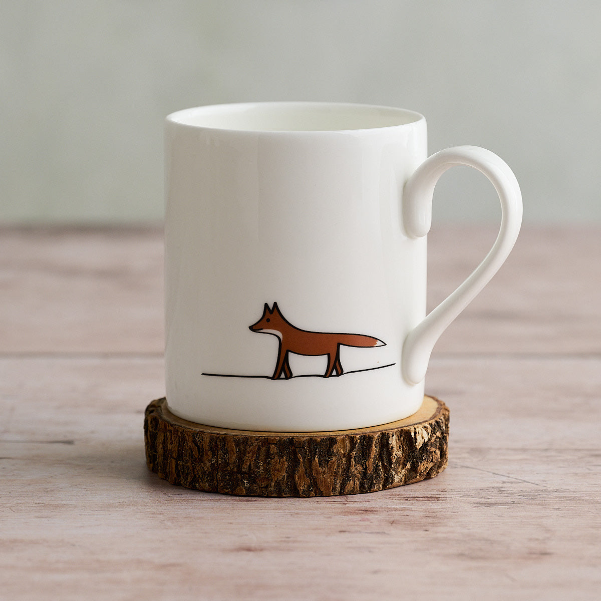 White mug with Fox illustration on a wooden coaster