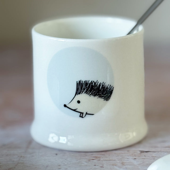 White fine bone china jam pot with a hedgehog design on a wooden surface