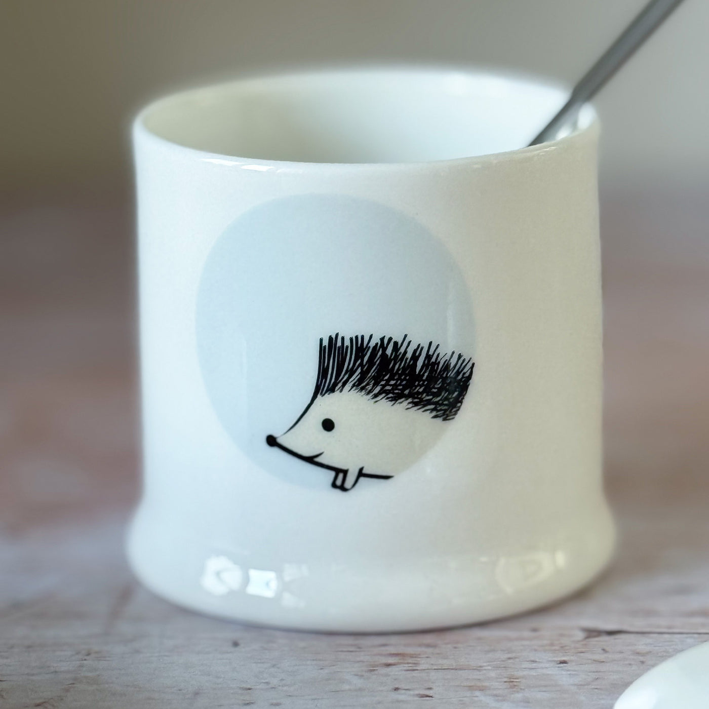 White fine bone china jam pot with a hedgehog design on a wooden surface