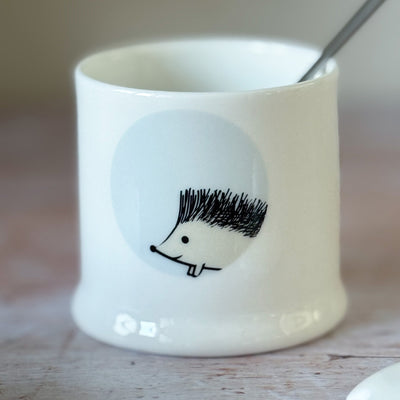 White fine bone china jam pot with a hedgehog design on a wooden surface
