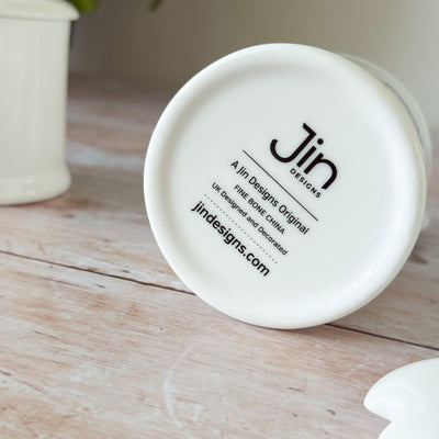 White fine bone china jam pot with backstamp of Jin Designs branding on a wooden surface