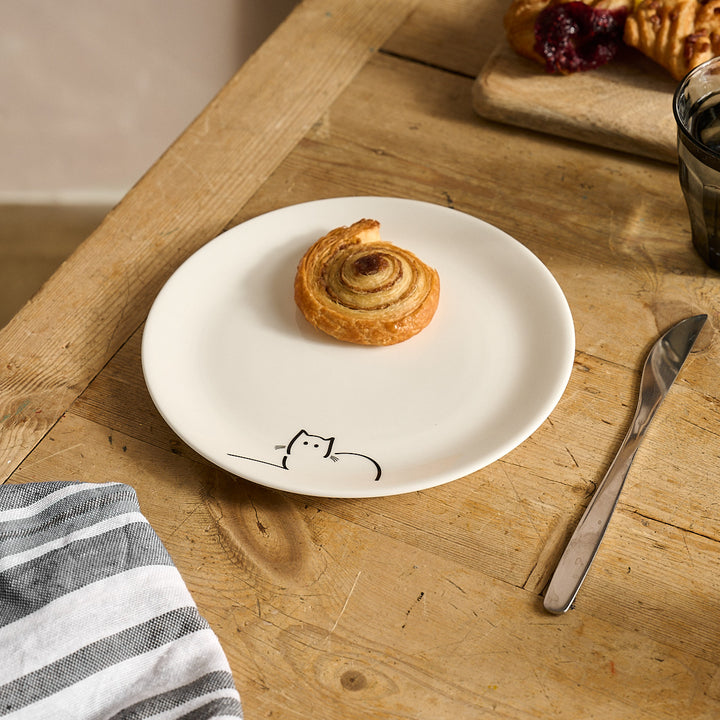 Cinnamon roll on a Loafing Cat Side Plate on a wooden table.