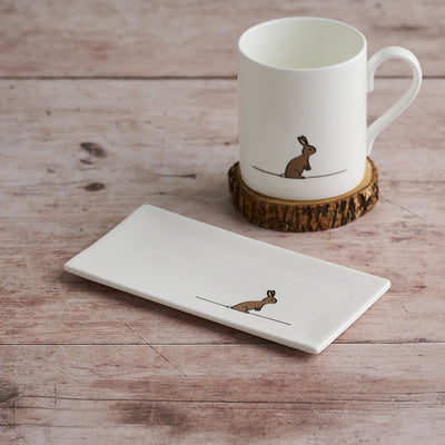 White mug and rectangular mini tray with rabbit design on a wooden surface