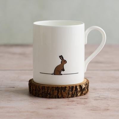 White mug with a rabbit illustration on a wooden coaster