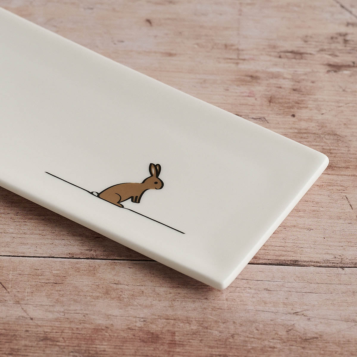 Rectangular white mini tray with a brown rabbit illustration on a wooden surface