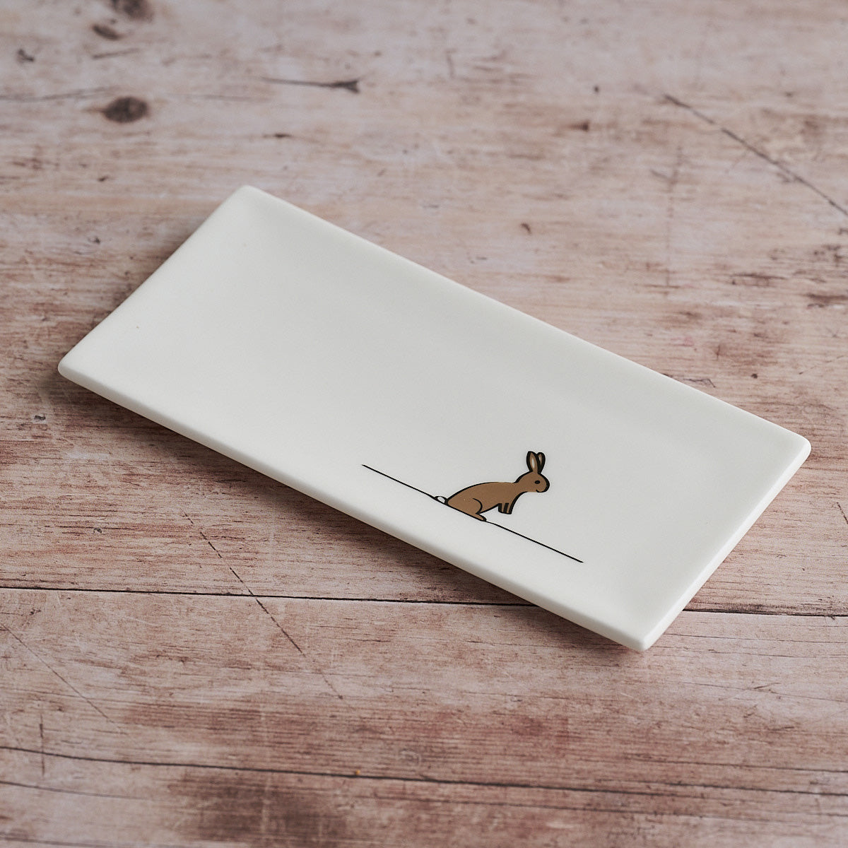 Rectangular white mini tray with a rabbit illustration on a wooden surface