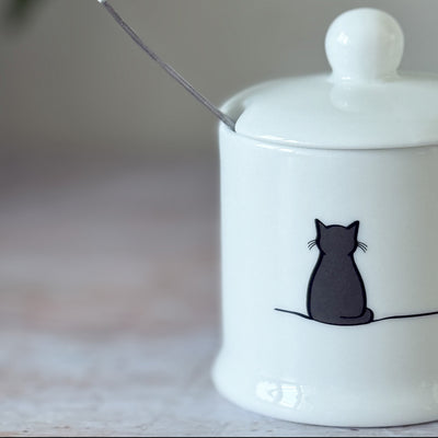 White fine bone china jam pot with a black cat illustration on a blurred background