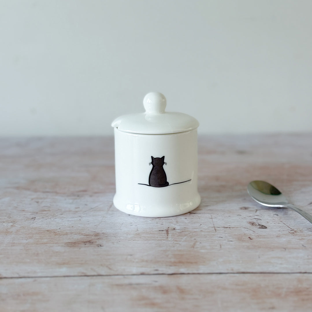 White fine bone china jam pot with a black cat illustration on a wooden surface