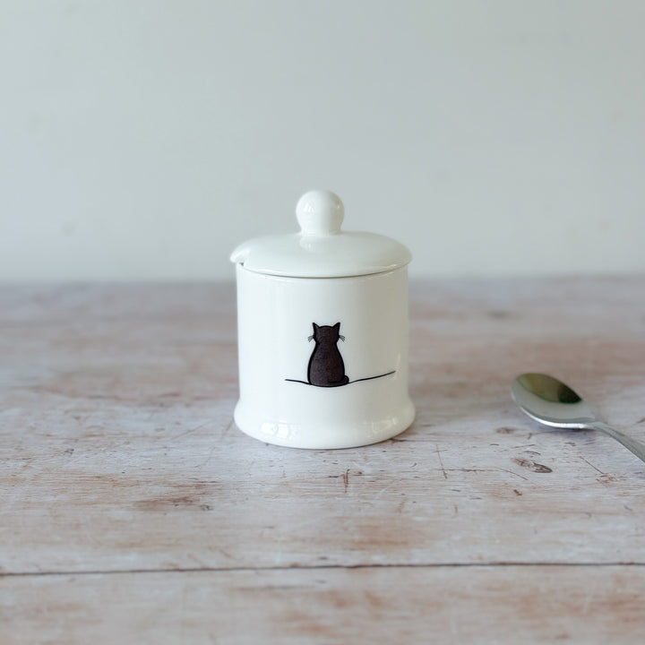 White fine bone china jam pot with a black cat illustration on a wooden surface