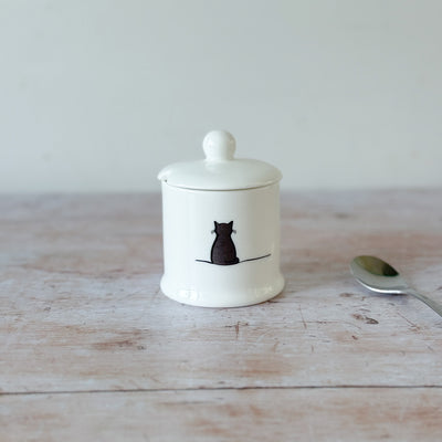 White fine bone china jam pot with a black cat illustration on a wooden surface