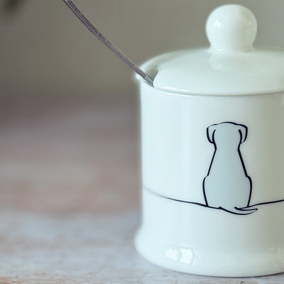 White fine bone china jam pot with a black line drawing of a sitting dog on a wooden surface