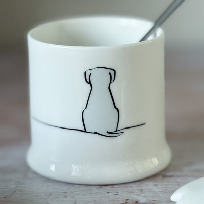 White fine bone china jam pot with a black line drawing of a sitting dog on a wooden surface