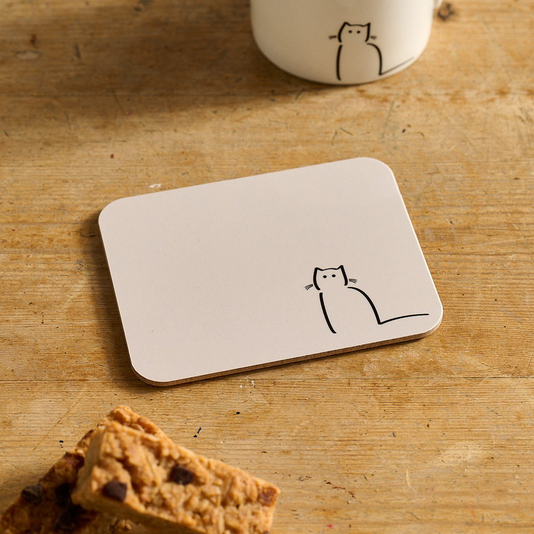 Waiting Cat Coaster with a cat design on a wooden surface with cookies and a mug.