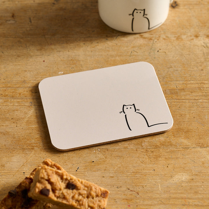 Waiting Cat Coaster with a cat design on a wooden surface with cookies and a mug.