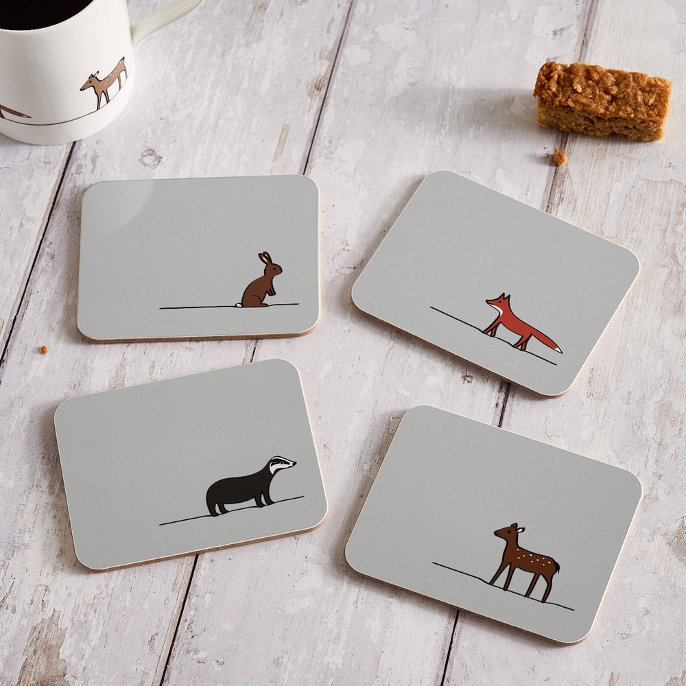 Set of four coasters with animal illustrations on a wooden surface.
