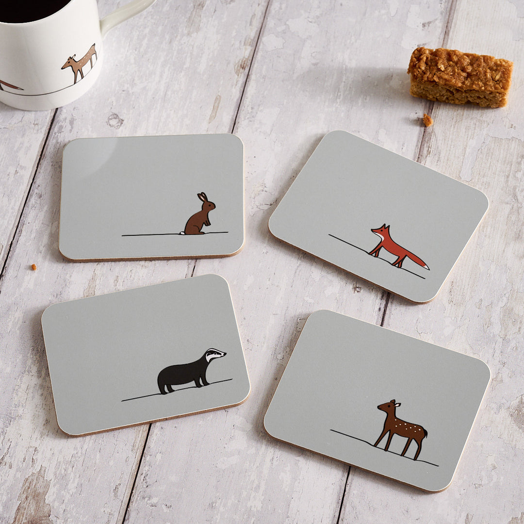 Set of four coasters with animal illustrations on a wooden surface.