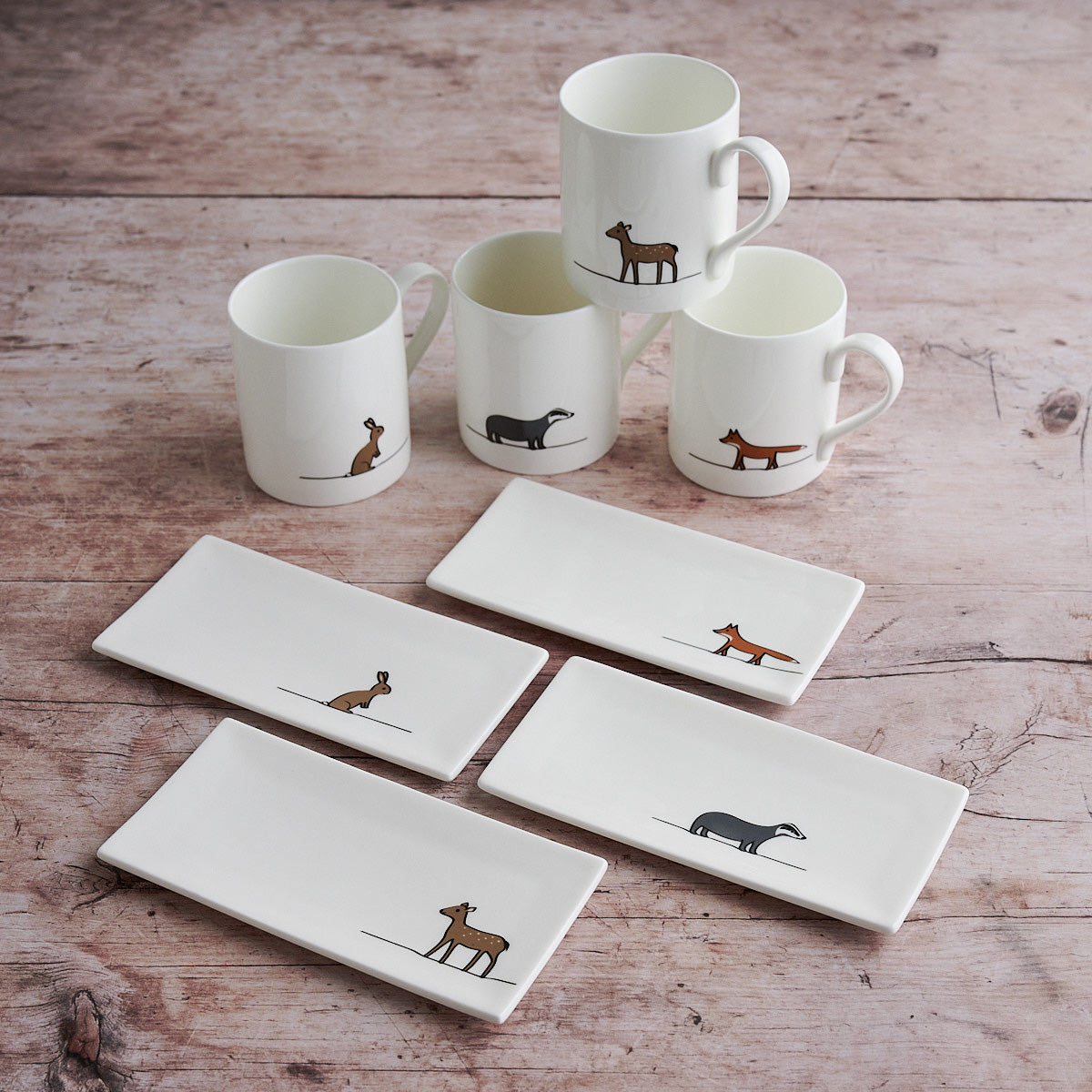 Set of Woodland mugs and mini trays with animal illustrations on a wooden surface