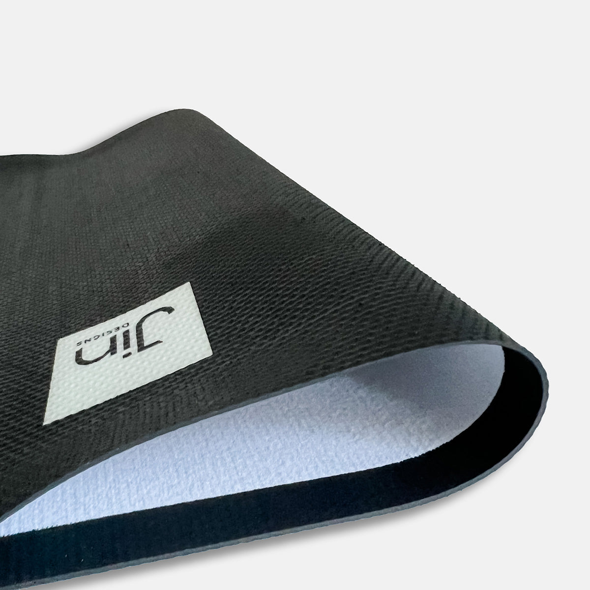 Anti-slip rubber backing on desk mat and Jin Designs logo on reverse
