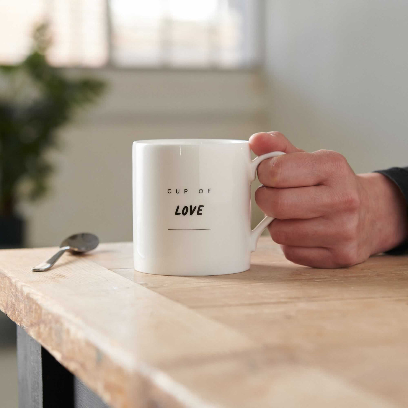 Cup of Love Mug on table with hand