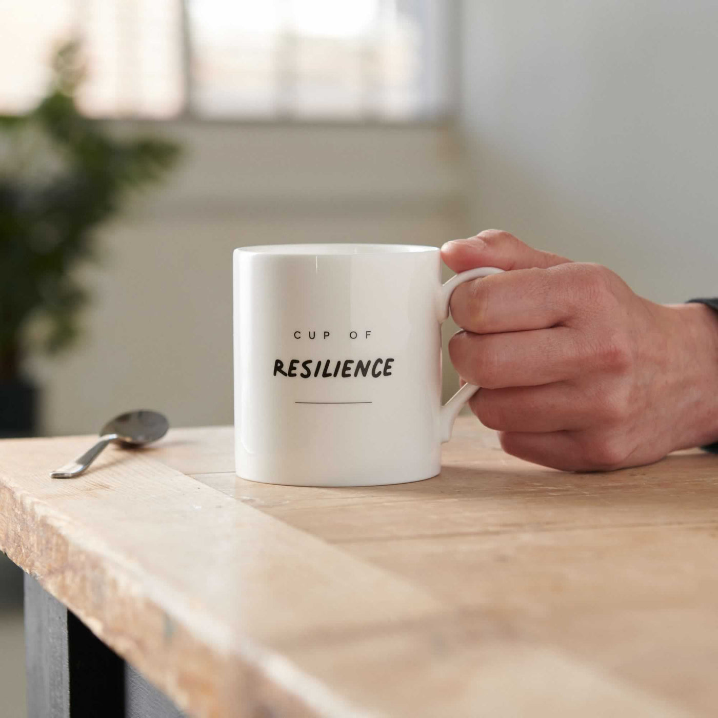 Cup of Resilience Mug on Table with hand