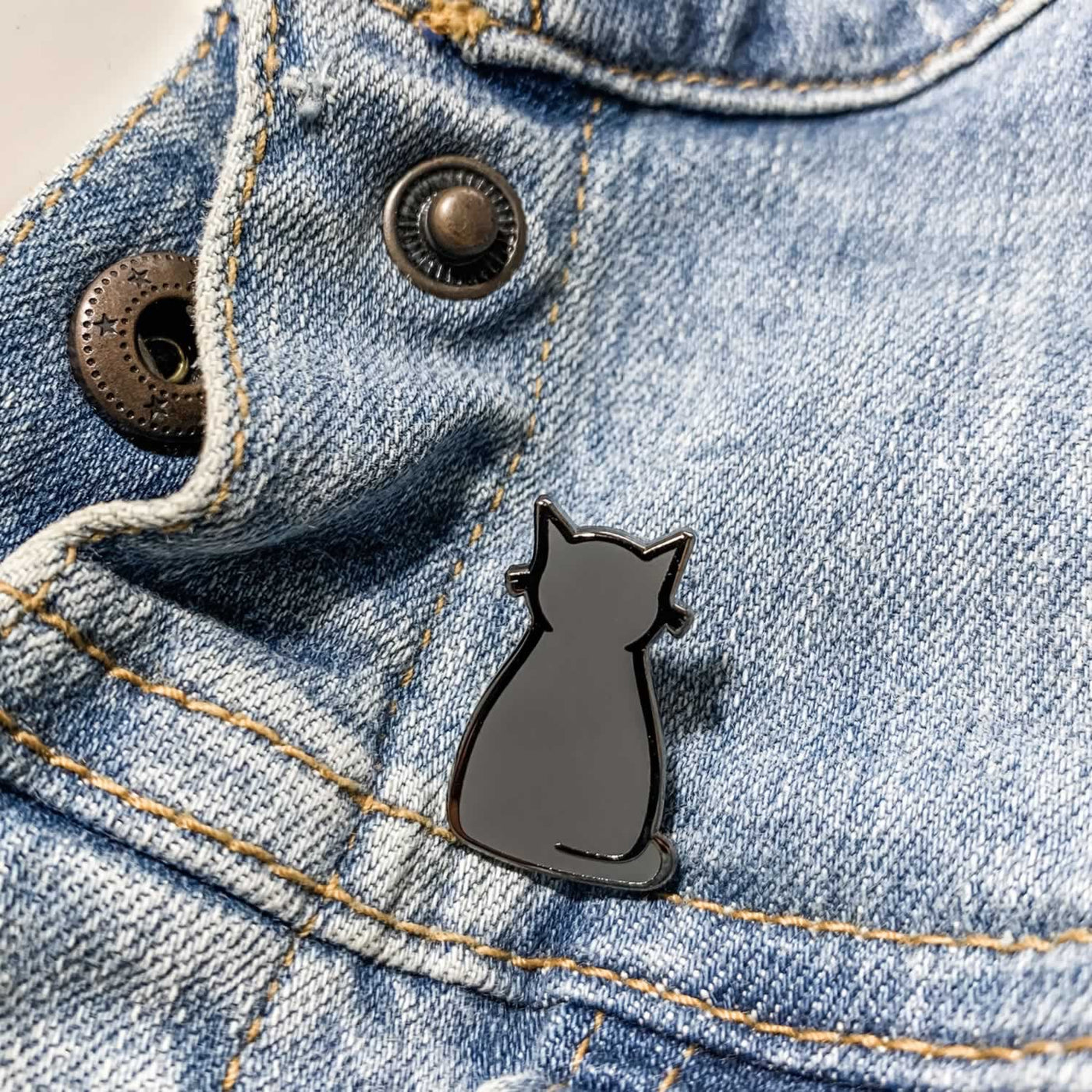 Sitting Cat Enamel Pin on Denim